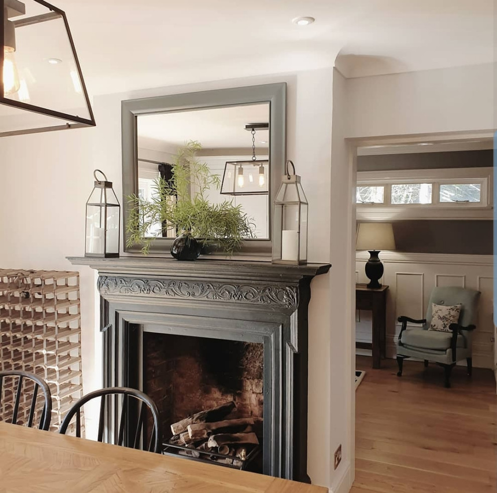 Large traditional open plan dining in Surrey with grey walls, light hardwood floors, a standard fireplace and a metal fireplace surround.