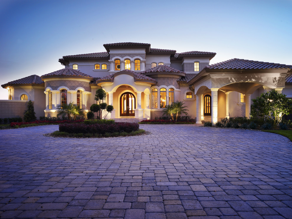 Photo of an expansive mediterranean two-storey stucco beige house exterior in Tampa with a hip roof and a tile roof.