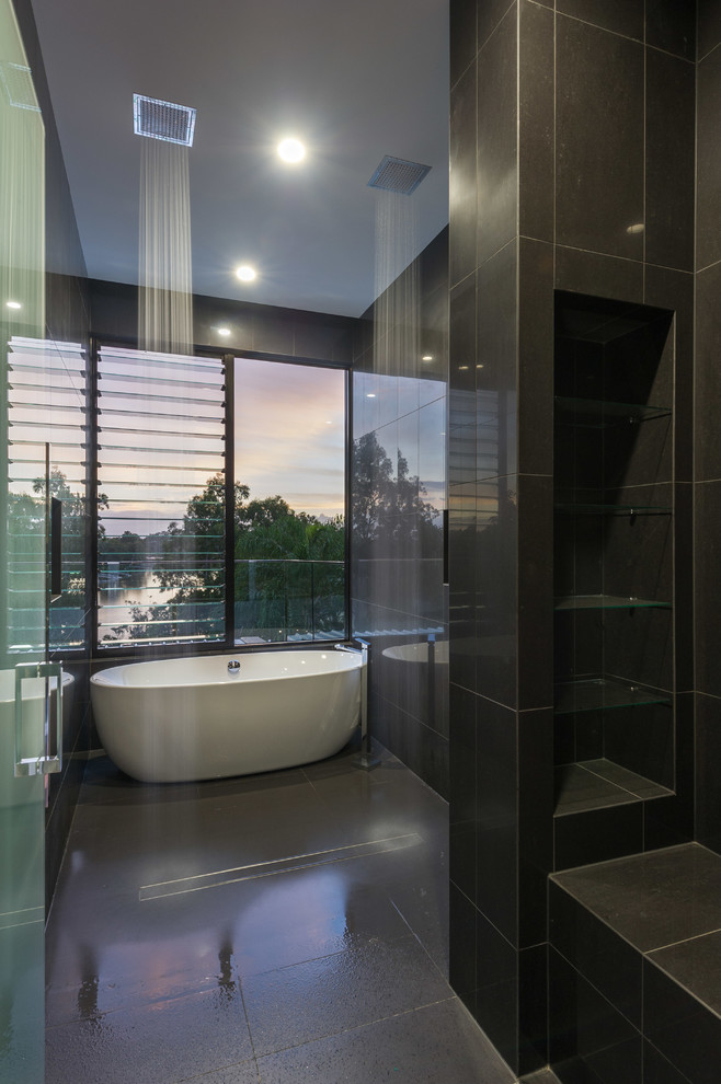 Inspiration for a contemporary bathroom in Brisbane with a freestanding tub, black tile, porcelain tile and black walls.