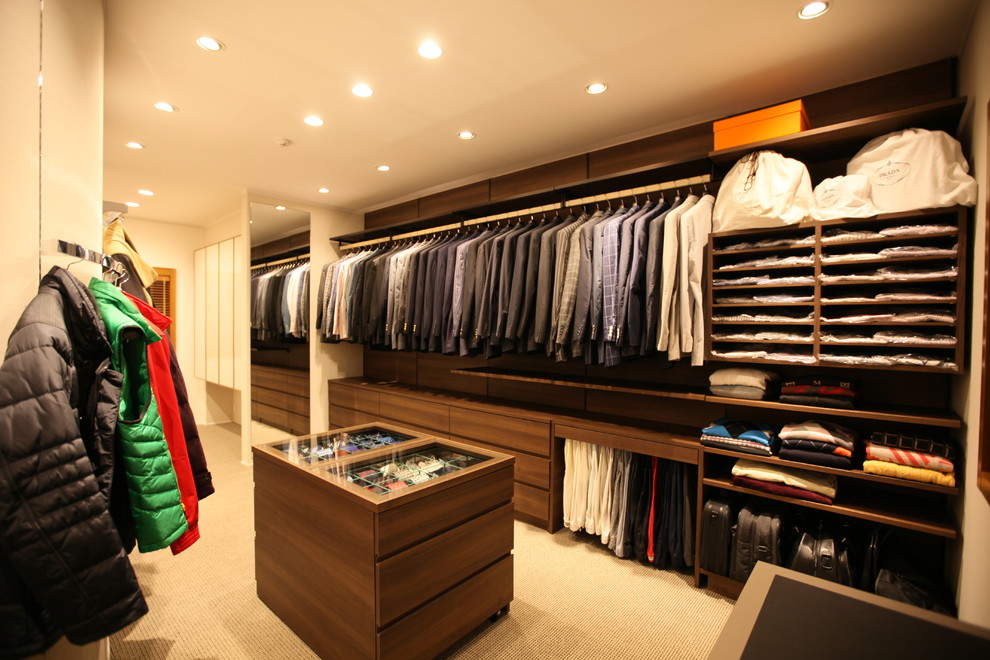 Ejemplo de vestidor de hombre contemporáneo con armarios con paneles lisos, puertas de armario de madera en tonos medios, moqueta y suelo marrón