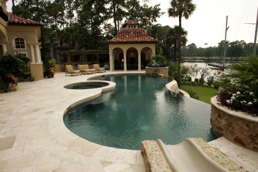 Inspiration for a mid-sized mediterranean backyard custom-shaped natural pool in Atlanta with a hot tub and natural stone pavers.