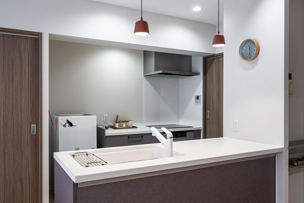 Cette photo montre une cuisine ouverte parallèle moderne avec une crédence grise, un électroménager en acier inoxydable, un sol en contreplaqué, îlot, un sol beige, un plan de travail blanc et un plafond en papier peint.