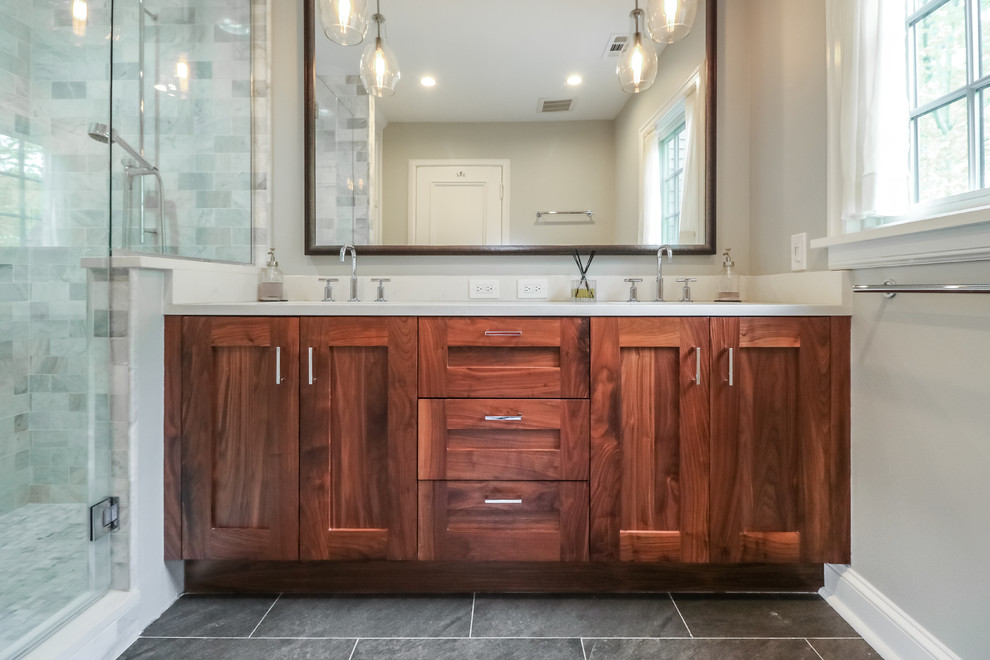 Mid-sized contemporary master bathroom in Kansas City with recessed-panel cabinets, medium wood cabinets, a two-piece toilet, gray tile, marble, grey walls, ceramic floors, an undermount sink, onyx benchtops, grey floor, a hinged shower door, a corner shower and white benchtops.