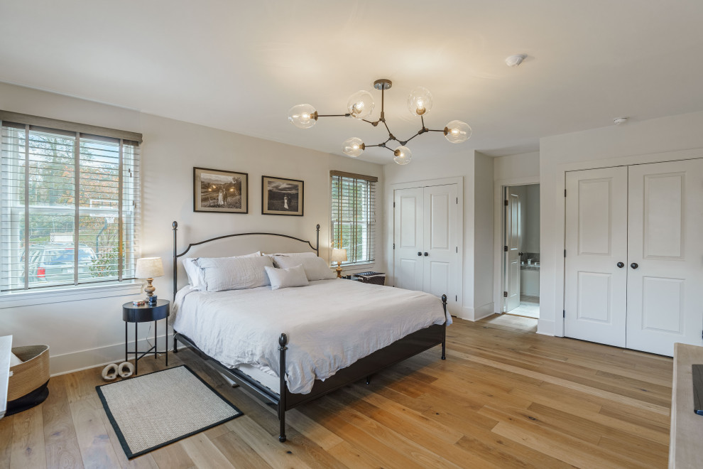 Photo of a large modern master bedroom in Other with white walls, light hardwood floors, no fireplace and brown floor.