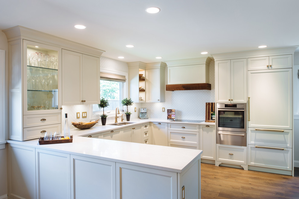 Inspiration for a mid-sized traditional u-shaped open plan kitchen in Vancouver with an undermount sink, shaker cabinets, white cabinets, quartz benchtops, white splashback, mosaic tile splashback, panelled appliances, medium hardwood floors and no island.