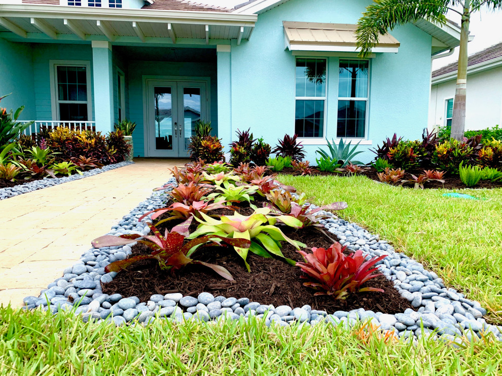 Design ideas for a mid-sized tropical front yard full sun formal garden in Miami with with rock feature and river rock.