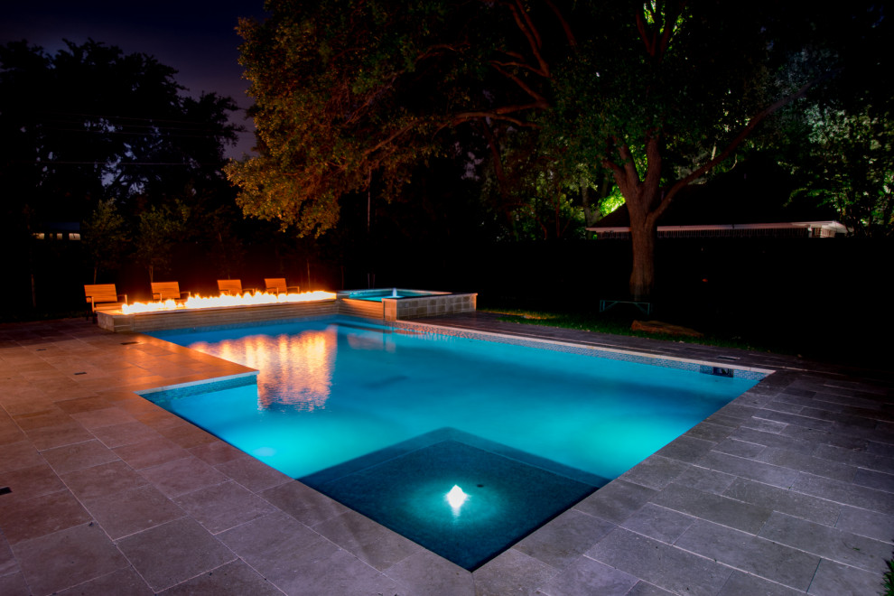 Inspiration for a mid-sized modern backyard custom-shaped lap pool in Dallas with a water feature and natural stone pavers.