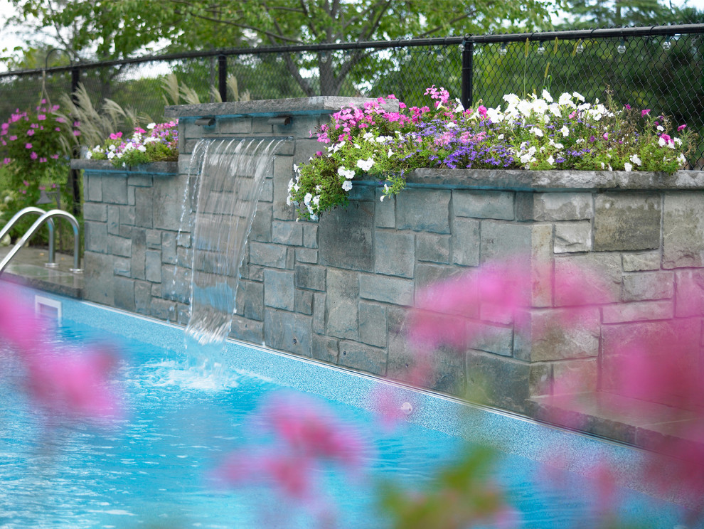 This is an example of a small modern backyard custom-shaped natural pool in Toronto with a water feature and brick pavers.