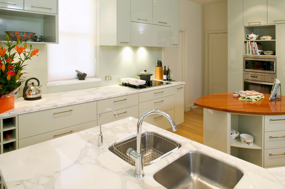 Photo of a traditional galley kitchen pantry in Perth with flat-panel cabinets, grey cabinets, wood benchtops, multiple islands, a double-bowl sink, mirror splashback, stainless steel appliances and medium hardwood floors.