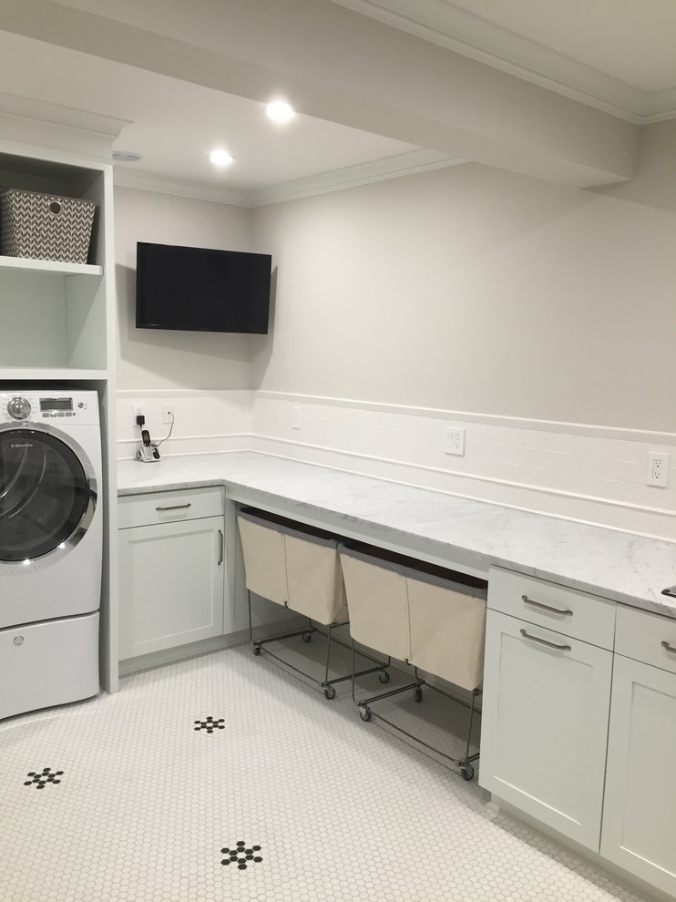 Design ideas for a large transitional l-shaped dedicated laundry room in New York with an undermount sink, shaker cabinets, white cabinets, marble benchtops, grey walls, ceramic floors, a side-by-side washer and dryer and white floor.