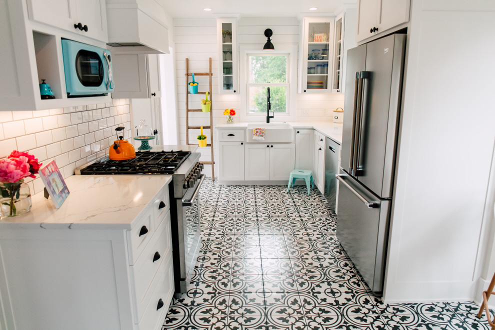 Small bohemian u-shaped enclosed kitchen in Seattle with a belfast sink, shaker cabinets, white cabinets, engineered stone countertops, white splashback, ceramic splashback, stainless steel appliances, porcelain flooring, no island, black floors and white worktops.