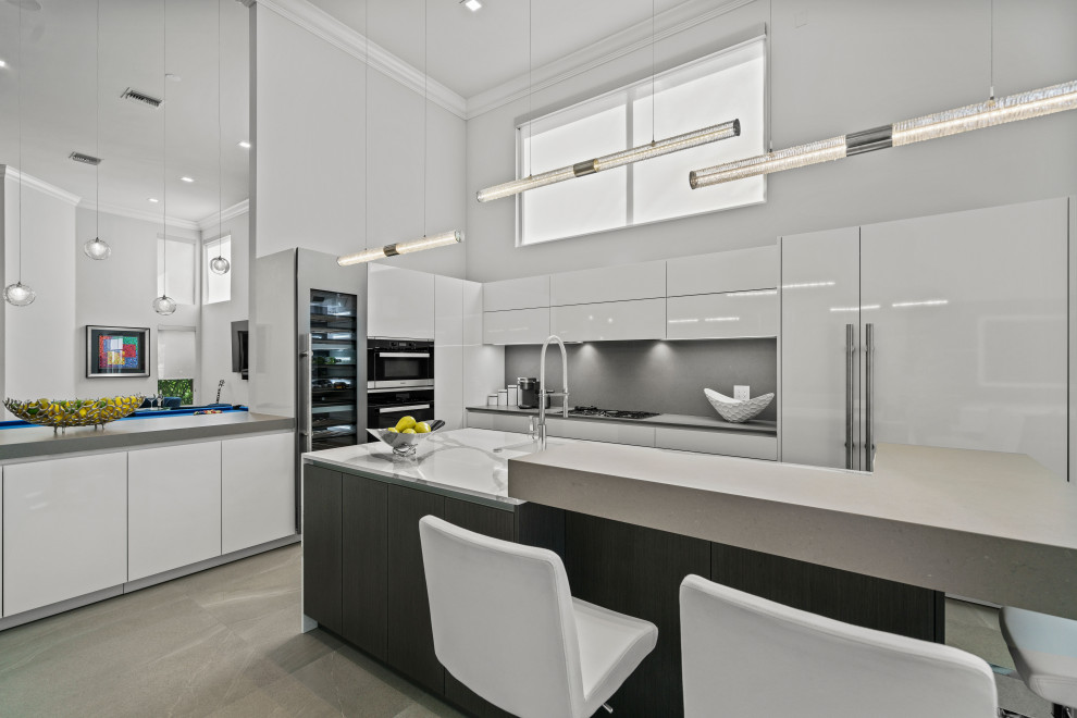 Mid-sized contemporary l-shaped open plan kitchen in Miami with a single-bowl sink, flat-panel cabinets, white cabinets, quartz benchtops, grey splashback, engineered quartz splashback, panelled appliances, porcelain floors, with island and multi-coloured benchtop.