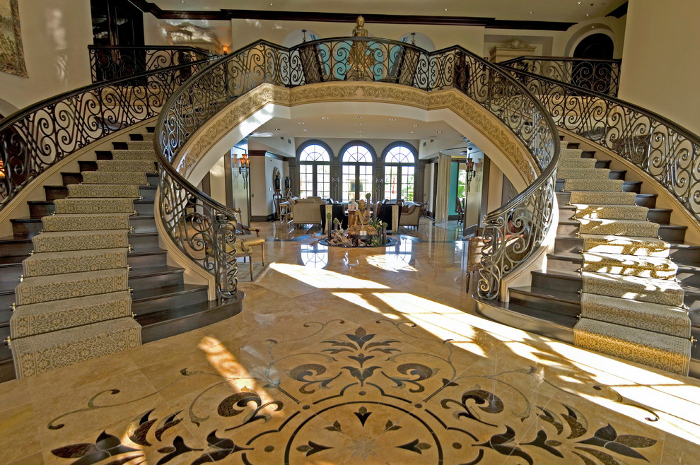 This is an example of an expansive traditional wood curved staircase in Los Angeles with wood risers.