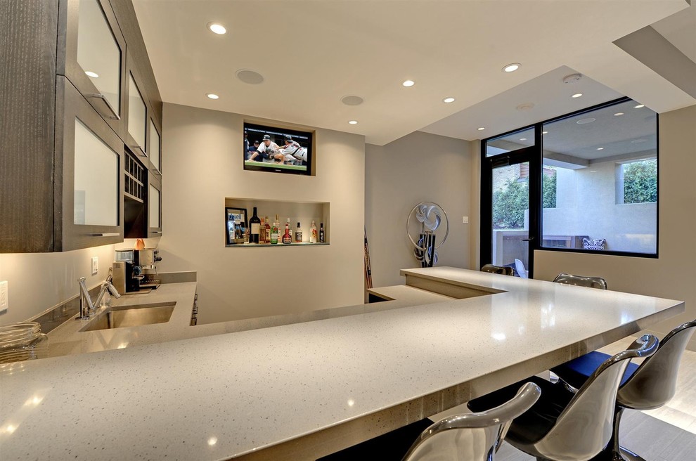 This is an example of a large contemporary u-shaped home bar in Minneapolis with an undermount sink, glass-front cabinets, grey cabinets and beige benchtop.