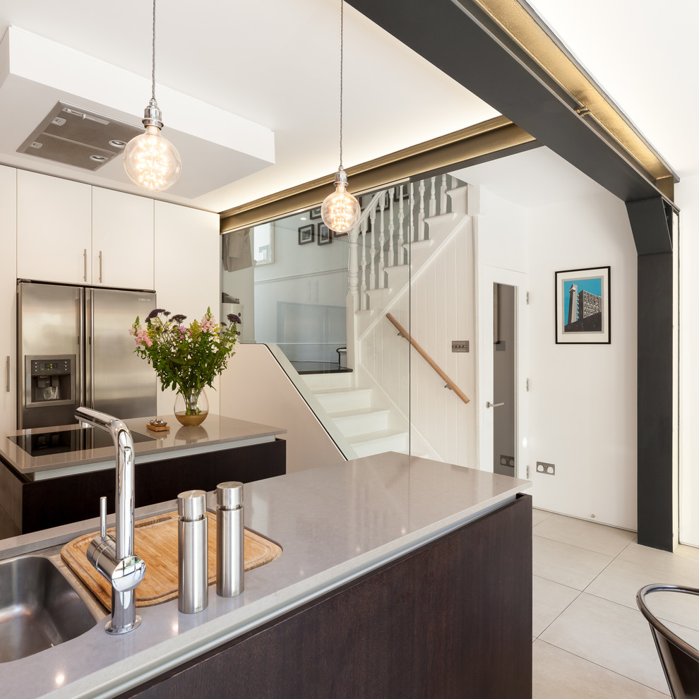 Photo of a mid-sized industrial u-shaped open plan kitchen in London with an integrated sink, flat-panel cabinets, dark wood cabinets, concrete benchtops, stainless steel appliances, ceramic floors, with island, beige floor and grey benchtop.