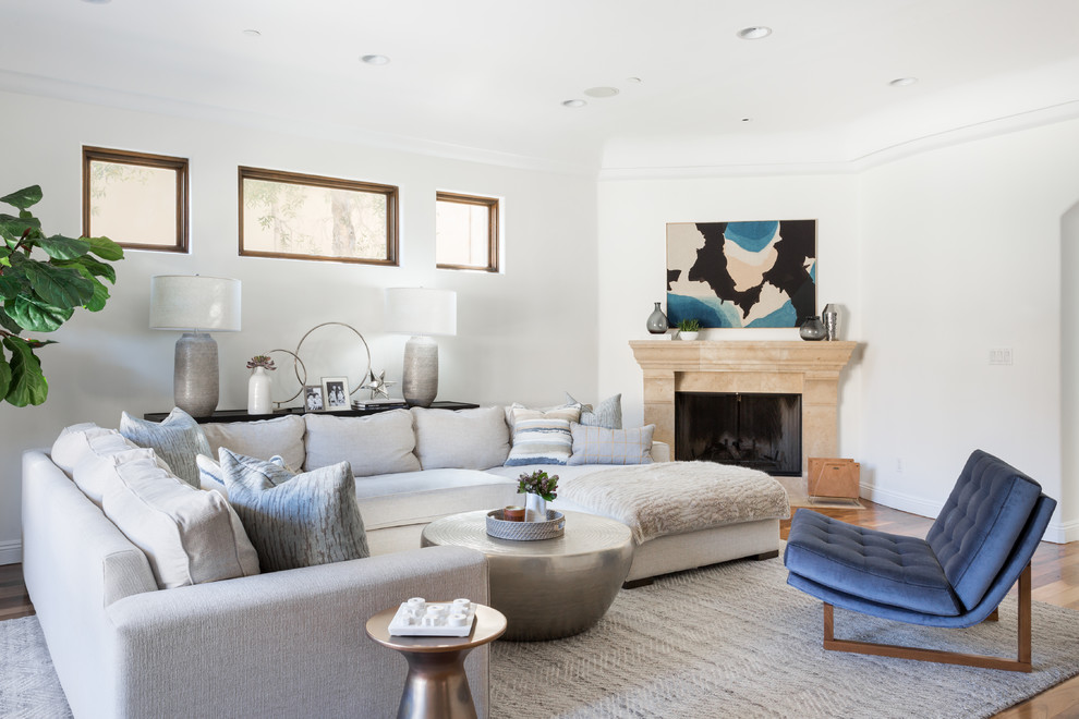 Large mediterranean open concept family room in Los Angeles with white walls, medium hardwood floors, a corner fireplace, a concrete fireplace surround and a wall-mounted tv.