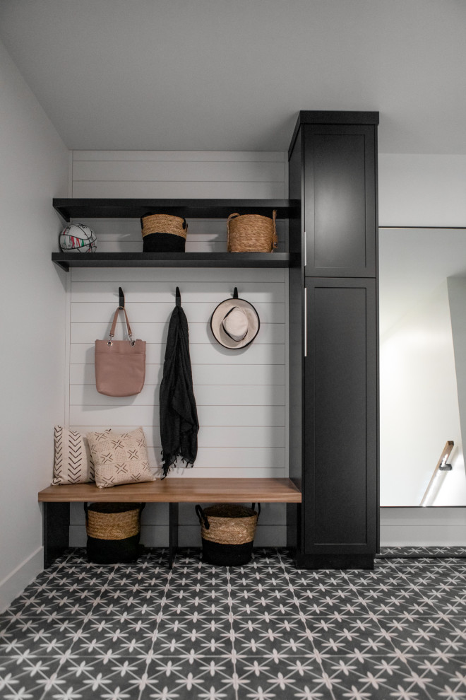 Inspiration for a large scandinavian utility room in Other with shaker cabinets, black cabinets, grey walls, ceramic floors, a stacked washer and dryer and grey floor.
