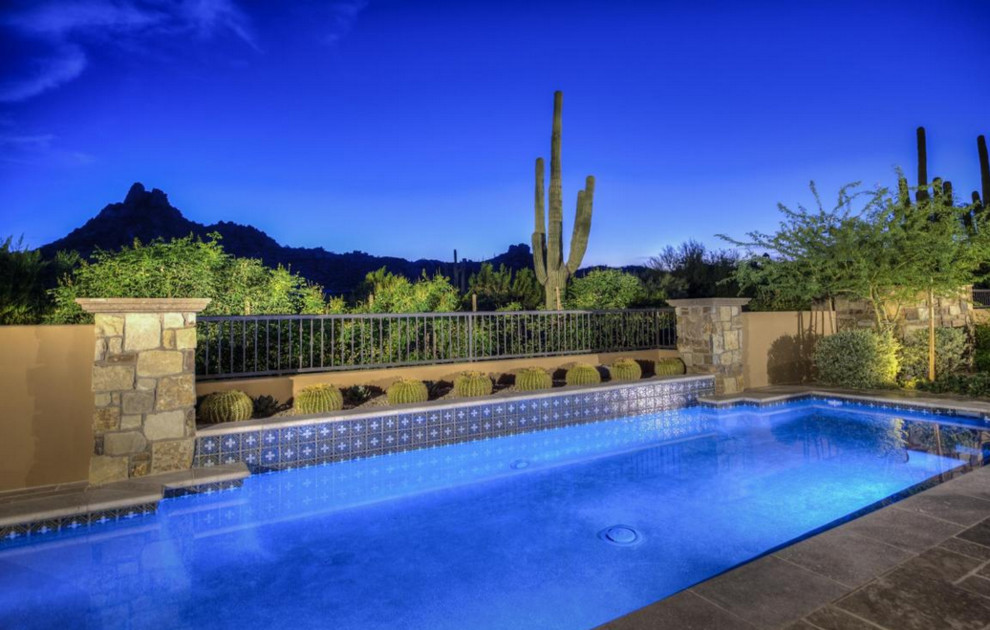 This is an example of an expansive transitional backyard rectangular natural pool in Phoenix with natural stone pavers.