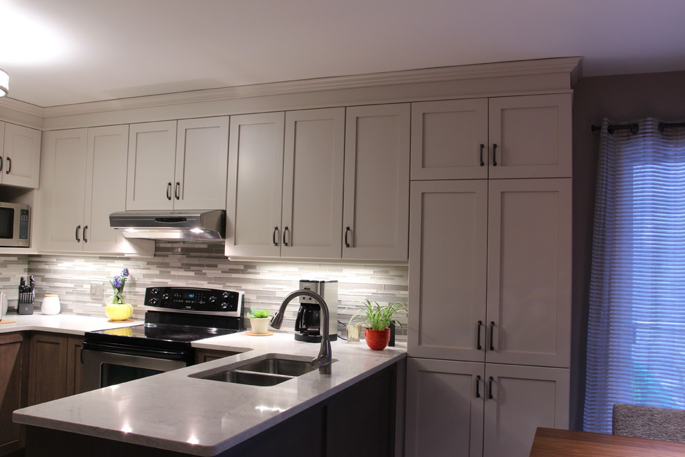 Eat-in kitchen - mid-sized transitional u-shaped ceramic tile and beige floor eat-in kitchen idea in Toronto with a double-bowl sink, shaker cabinets, gray cabinets, solid surface countertops, gray backsplash, glass sheet backsplash, stainless steel appliances and no island