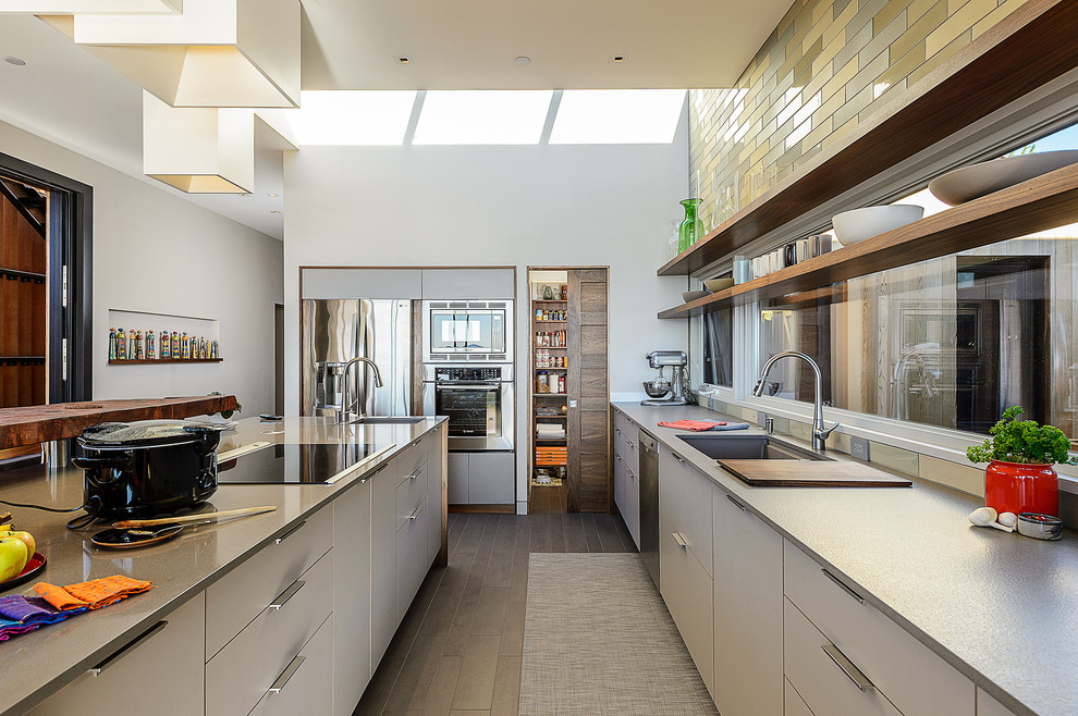 This is an example of a midcentury galley open plan kitchen in San Francisco with stainless steel appliances, an undermount sink, flat-panel cabinets, white cabinets, multi-coloured splashback and subway tile splashback.