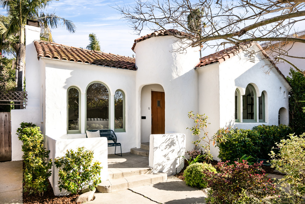 Photo of a mediterranean one-storey white house exterior in Los Angeles with a gable roof and a tile roof.