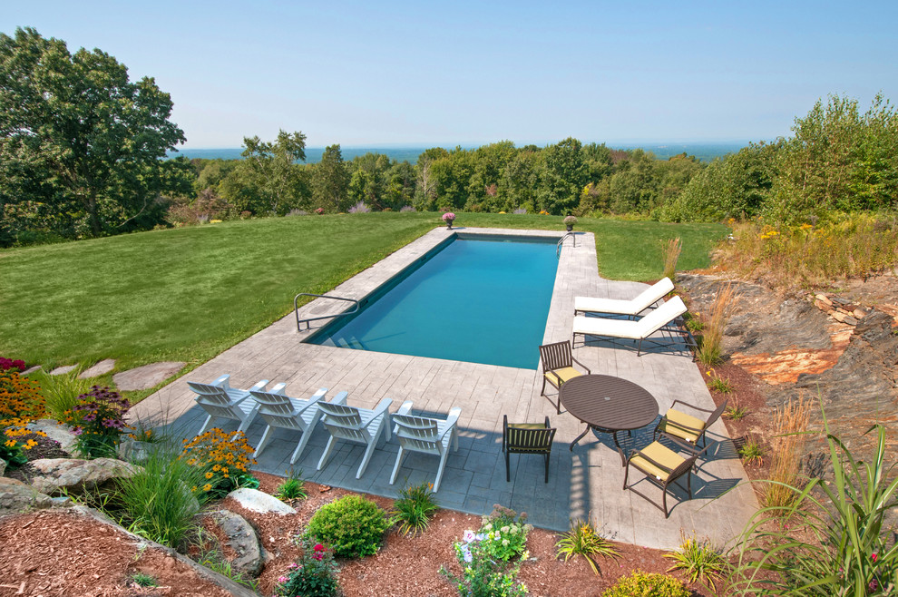 Example of a backyard stamped concrete and rectangular lap pool design in Boston