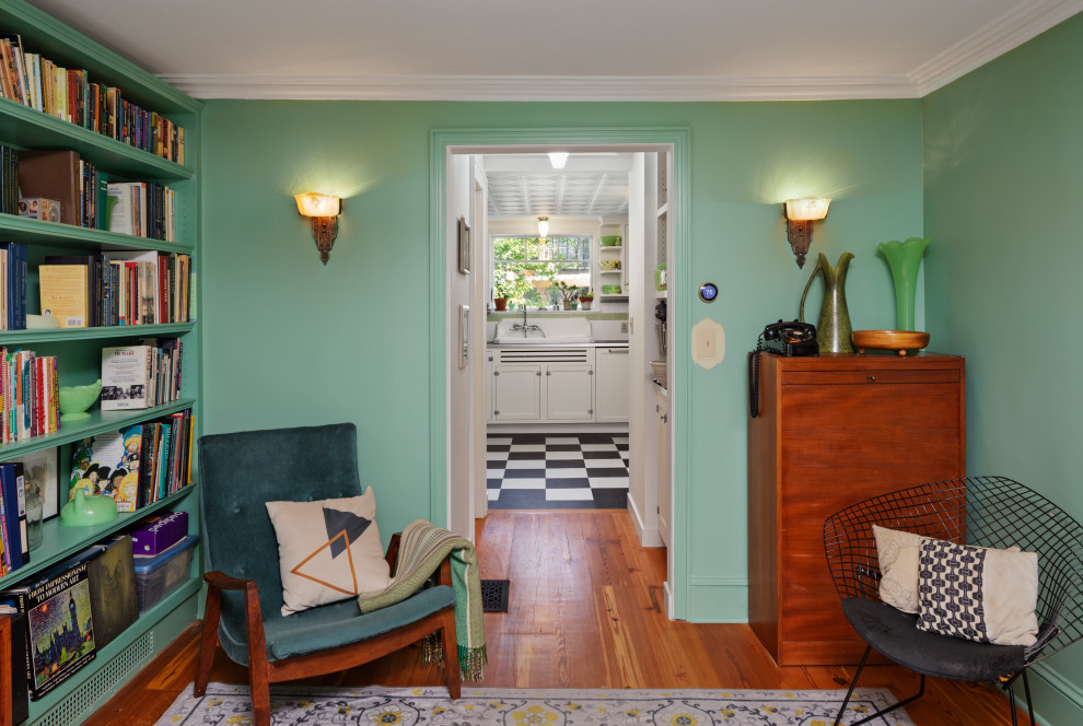 Cette image montre une petite salle de séjour victorienne fermée avec une bibliothèque ou un coin lecture, un mur vert, un sol en bois brun et un sol marron.