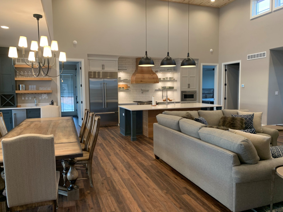 Large mountain style single-wall vinyl floor and brown floor eat-in kitchen photo with shaker cabinets, white cabinets, quartz countertops, white backsplash, subway tile backsplash, stainless steel appliances, an island and white countertops