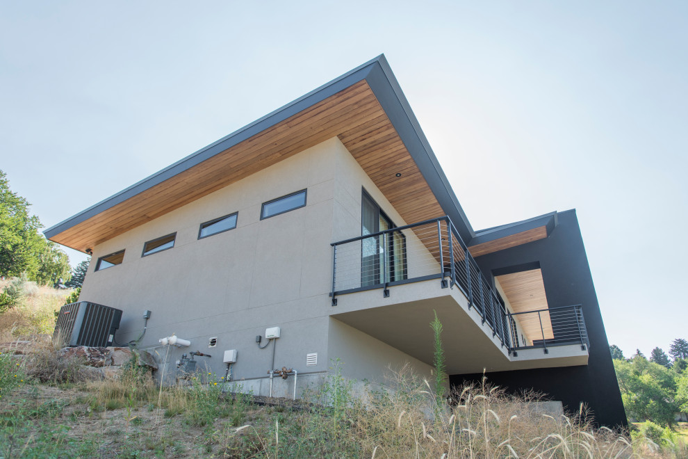 This is an example of a mid-sized contemporary two-storey stucco grey house exterior in Boise with a butterfly roof and a metal roof.