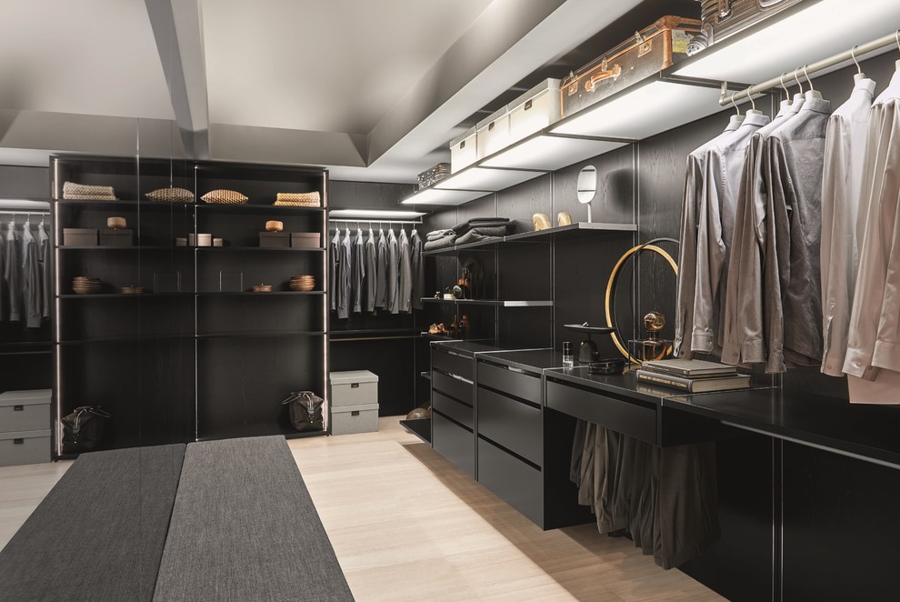 Photo of a mid-sized contemporary men's walk-in wardrobe in Stuttgart with black cabinets, light hardwood floors and beige floor.
