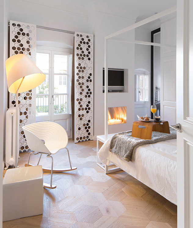 Design ideas for a mid-sized scandinavian master bedroom in Florence with white walls, light hardwood floors and a standard fireplace.