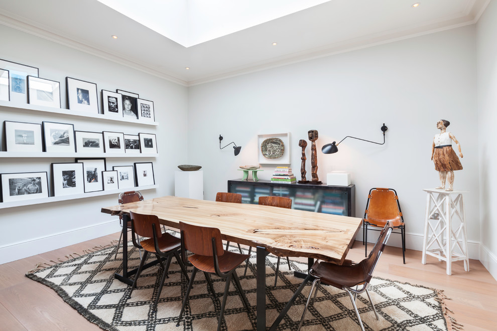 Inspiration for a mid-sized eclectic dining room in London with white walls and light hardwood floors.