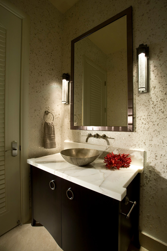 Photo of a mid-sized transitional powder room in Miami with a vessel sink, furniture-like cabinets, black cabinets, beige walls, travertine floors, marble benchtops, beige floor and white benchtops.