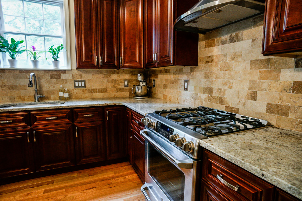 Foto på ett beige kök, med en undermonterad diskho, luckor med upphöjd panel, röda skåp, granitbänkskiva, beige stänkskydd, stänkskydd i stenkakel, ljust trägolv, en köksö och gult golv