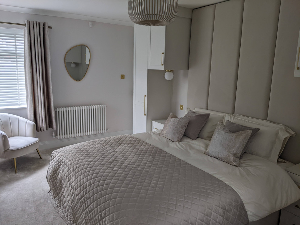 Photo of a mid-sized modern master bedroom in Manchester with beige walls and carpet.