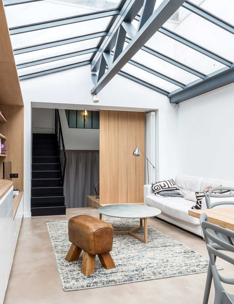 This is an example of a contemporary conservatory in Paris with concrete flooring, a glass ceiling and beige floors.
