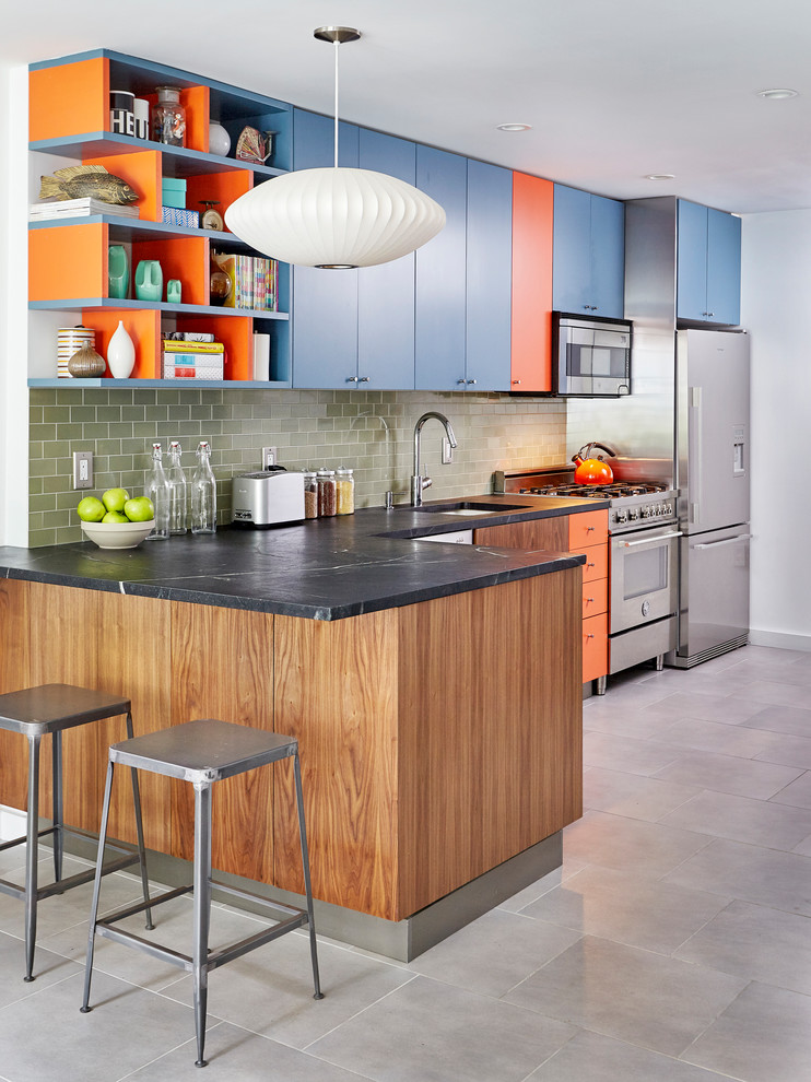 This is an example of a large contemporary l-shaped kitchen in New York with flat-panel cabinets, blue cabinets, a peninsula, an undermount sink, green splashback, subway tile splashback, stainless steel appliances, grey floor, soapstone benchtops and porcelain floors.