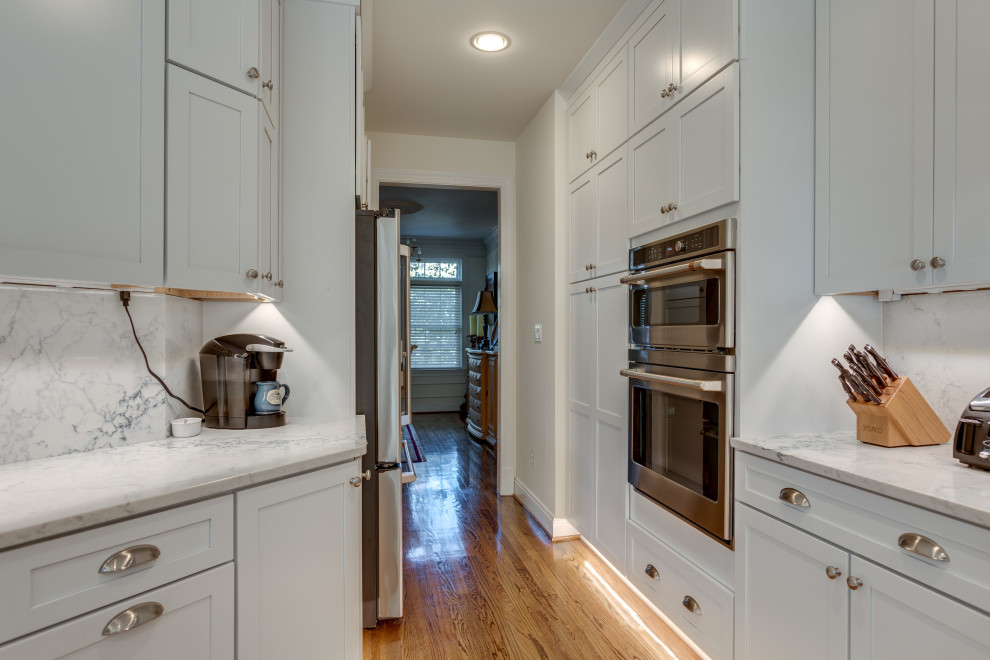 Small transitional u-shaped kitchen in DC Metro with an undermount sink, shaker cabinets, quartz benchtops, stainless steel appliances and a peninsula.