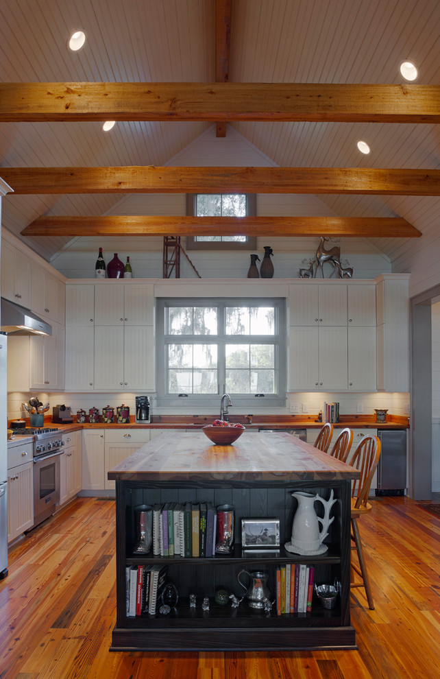 Photo of a large country l-shaped eat-in kitchen in Charleston with a farmhouse sink, louvered cabinets, white cabinets, wood benchtops, white splashback, stainless steel appliances, light hardwood floors and with island.