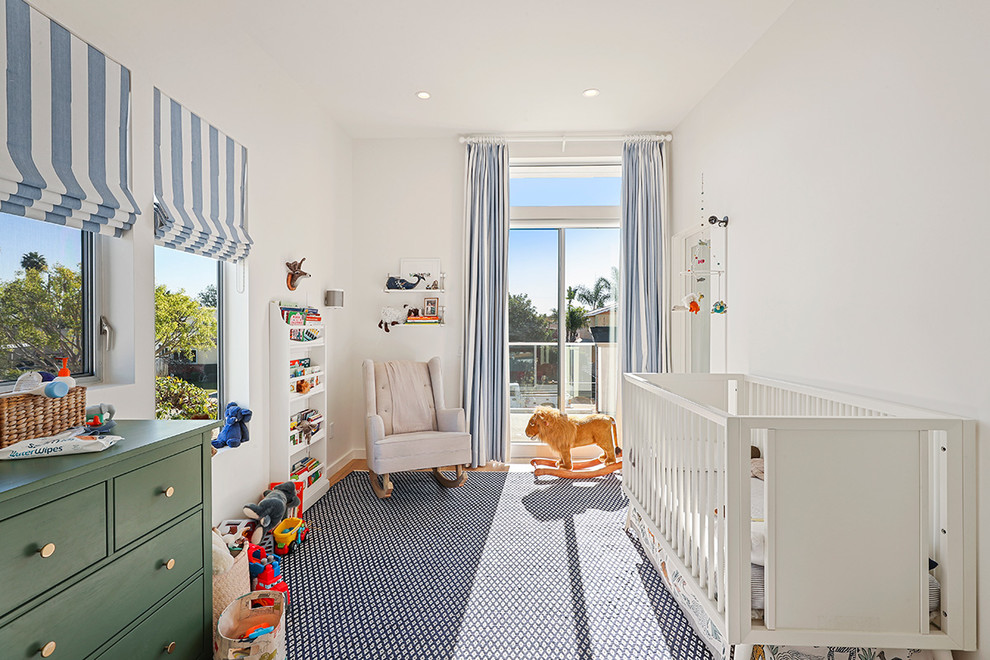 Photo of a large modern nursery in Los Angeles with white walls, light hardwood floors and brown floor.