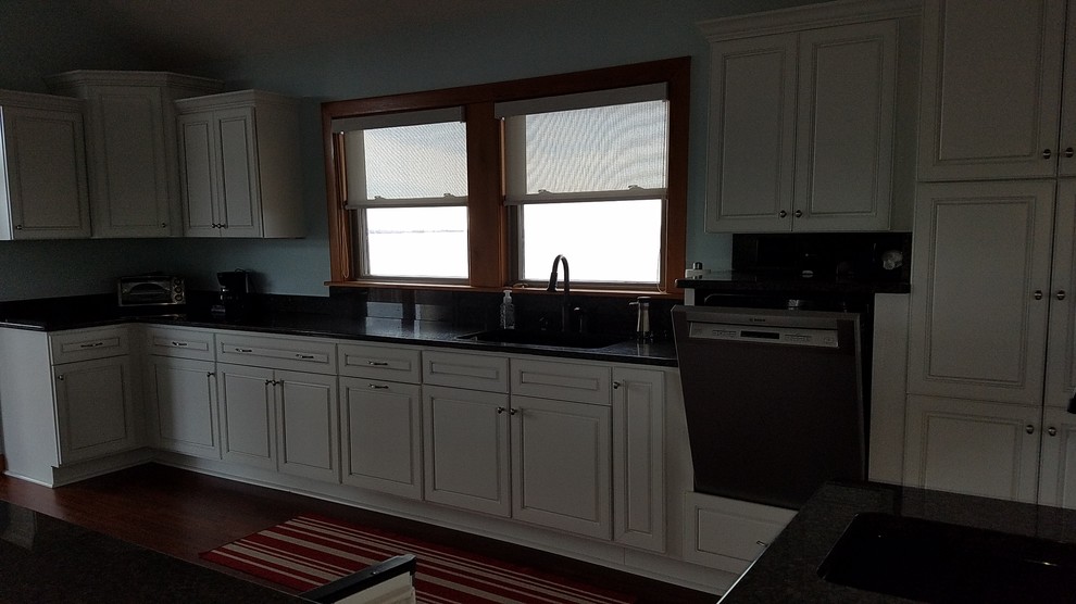 Transitional l-shaped kitchen photo with an undermount sink, raised-panel cabinets, white cabinets, granite countertops, stainless steel appliances and a peninsula