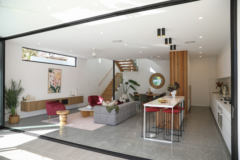 Modelo de salón abierto actual grande con paredes blancas, suelo de cemento y suelo gris