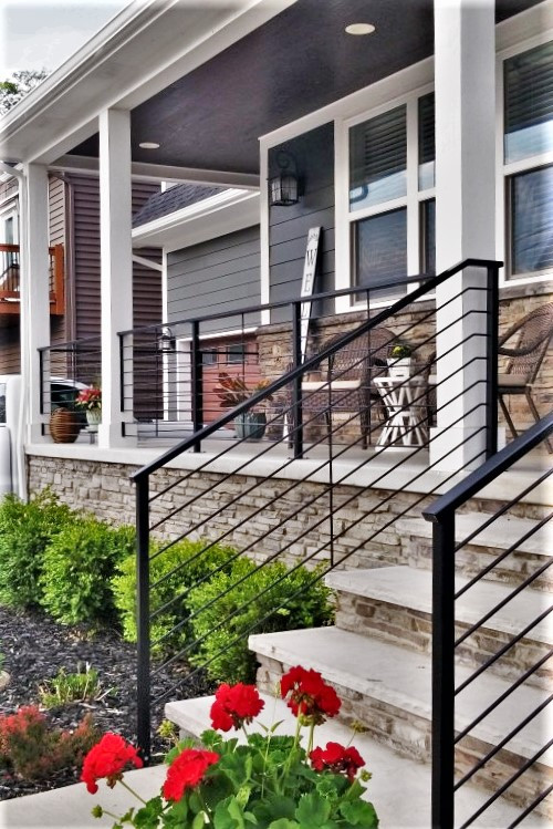 This is an example of a mid-sized contemporary front yard verandah in Detroit with with columns, brick pavers, a roof extension and metal railing.