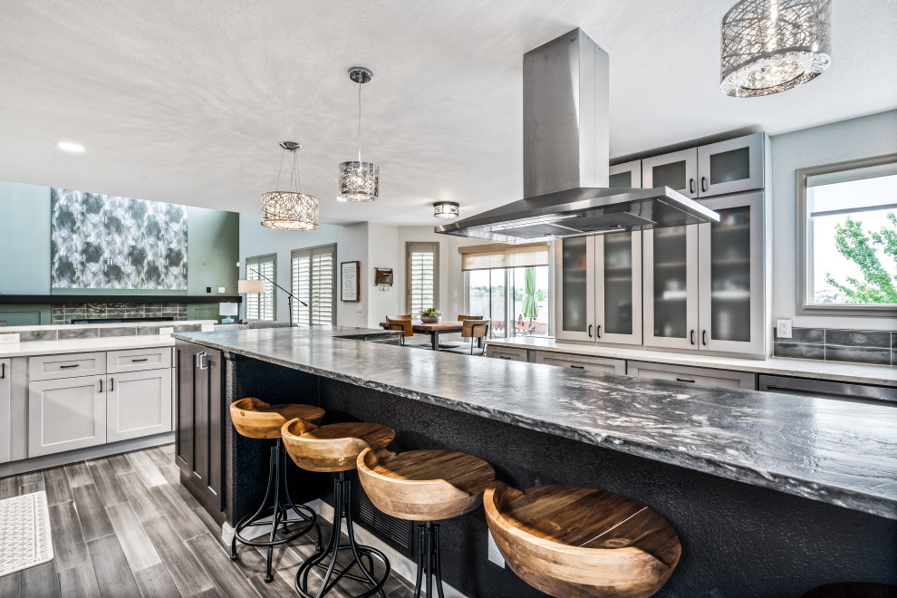 Inspiration for a large transitional l-shaped eat-in kitchen in Denver with an undermount sink, shaker cabinets, grey cabinets, granite benchtops, green splashback, ceramic splashback, stainless steel appliances, bamboo floors, with island, brown floor and multi-coloured benchtop.