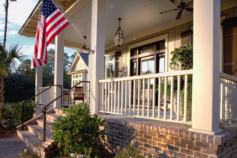 Photo of a large traditional front yard verandah in Charleston with brick pavers.