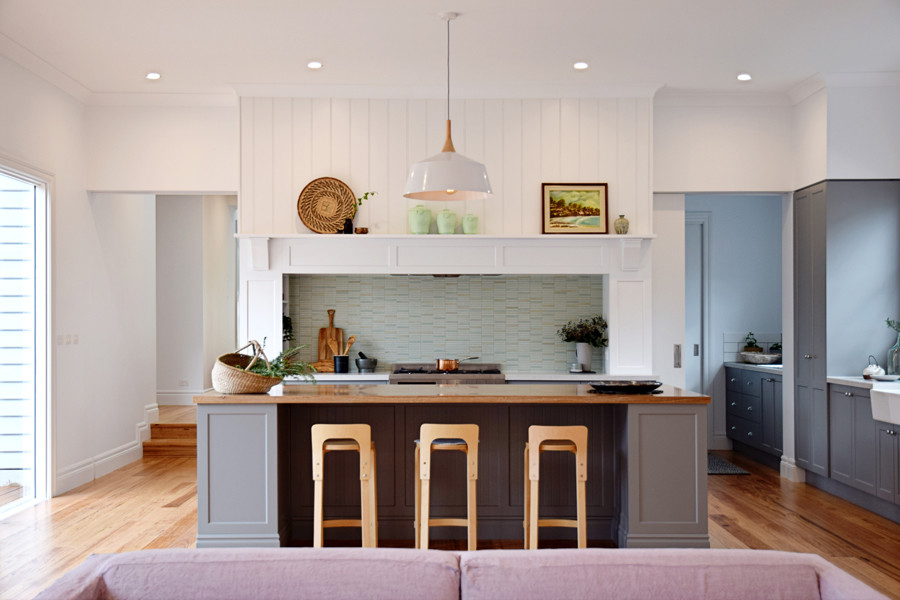 Inspiration for a large traditional galley open plan kitchen in Melbourne with a farmhouse sink, shaker cabinets, grey cabinets, quartz benchtops, white splashback, ceramic splashback, stainless steel appliances, light hardwood floors and with island.