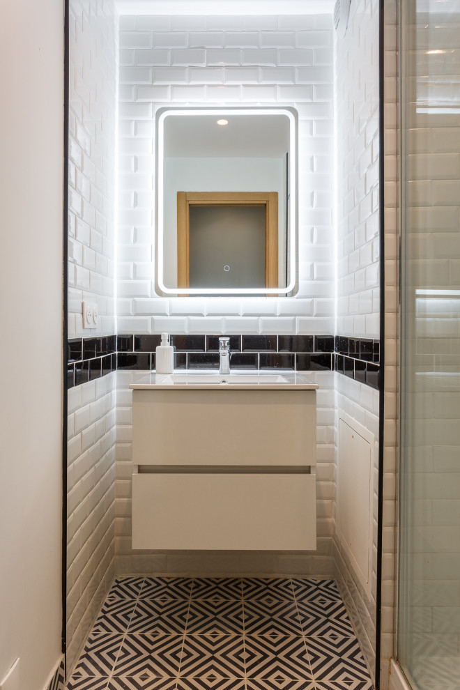 Inspiration for a small contemporary shower room bathroom in Paris with flat-panel cabinets, white cabinets, an alcove shower, a two-piece toilet, white tiles, black tiles, black and white tiles, metro tiles, white walls, cement flooring, a wall-mounted sink, black floors, white worktops, a single sink and a floating vanity unit.