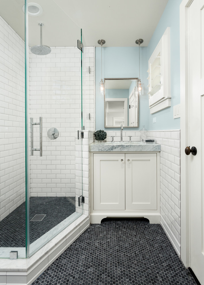 This is an example of a small transitional 3/4 bathroom in Orange County with shaker cabinets, white cabinets, a corner shower, white tile, subway tile, blue walls, an undermount sink, marble benchtops, black floor, a hinged shower door and grey benchtops.