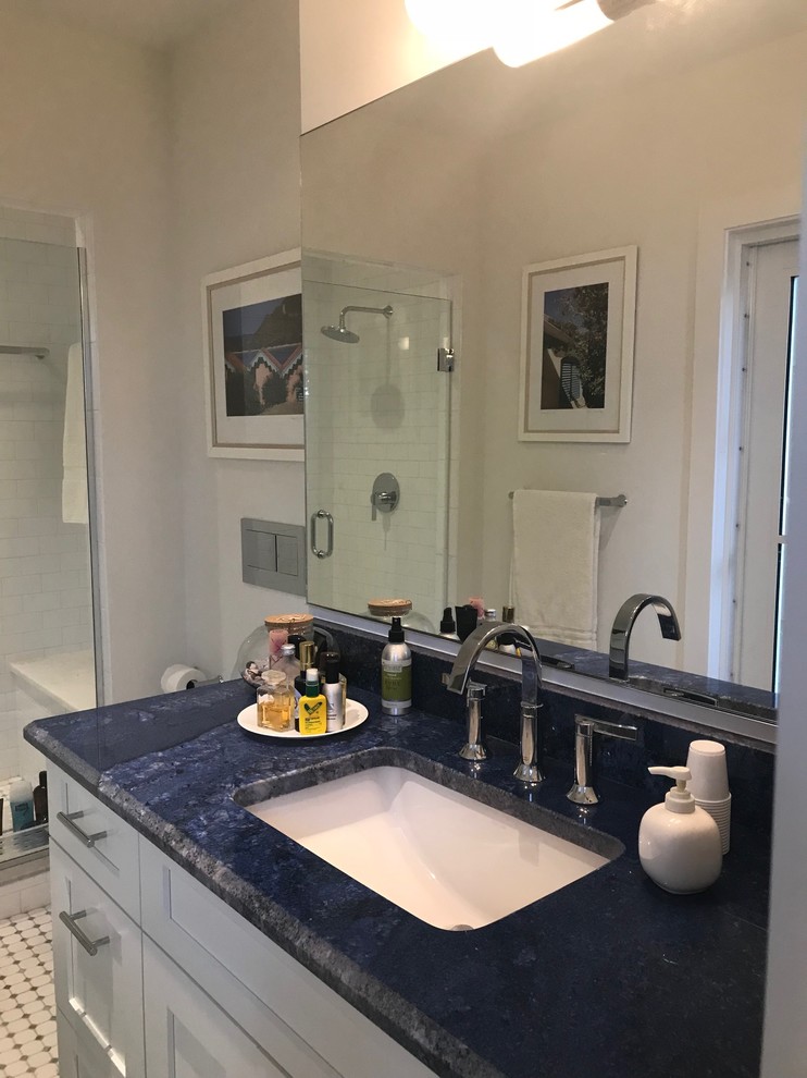 Photo of a mid-sized beach style 3/4 bathroom in Miami with recessed-panel cabinets, white cabinets, an open shower, white tile, ceramic tile, white walls, ceramic floors, an integrated sink, granite benchtops, multi-coloured floor, a hinged shower door, blue benchtops and a one-piece toilet.