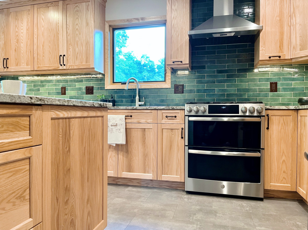 Example of a mid-sized transitional u-shaped vinyl floor and gray floor kitchen pantry design with an undermount sink, shaker cabinets, light wood cabinets, granite countertops, green backsplash, porcelain backsplash, stainless steel appliances, a peninsula and gray countertops